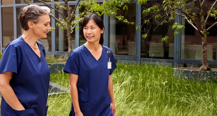 Afbeelding van twee zorgprofessionals buiten. Coloplast biedt darmspoel-opties met hoog als laag volume 