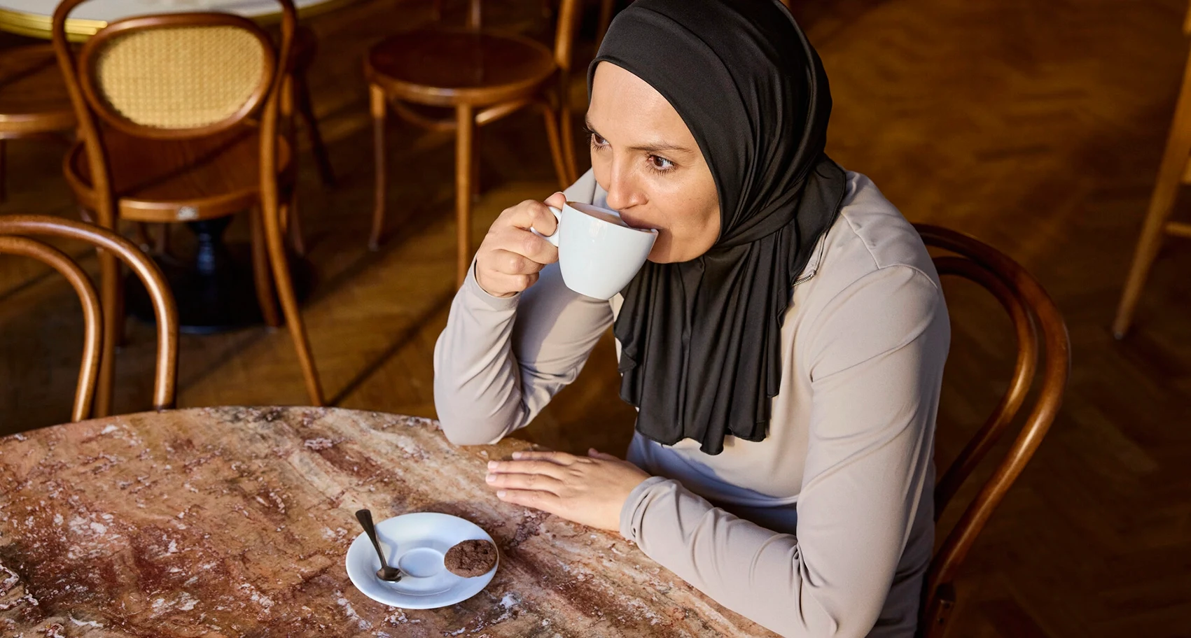 Portretfoto van Fikria zittend in een koffiebar. Fikria leeft met MS en darmklachten maken daar onderdeel van uit. Ze gebruikt Peristeen Light om haar klachten onder cotrole te krijgen. 