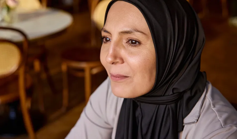 Foto van Fikria in een café. Fikria’s darmklachten zijn grotendeels zijn grotendeels het gevolg van haar MS en hebben hun tol geëist op haar kwaliteit van leven. 