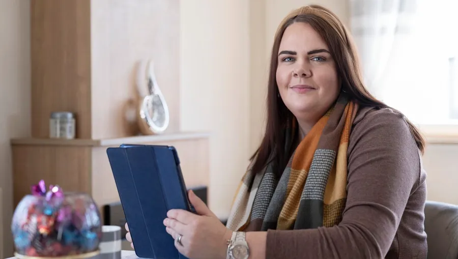 Foto van Sarah die aan een tafel zit. Pas vier jaar na haar eerste diagnose legde Sarah het verband tussen haar blaasklachten en haar MS. 