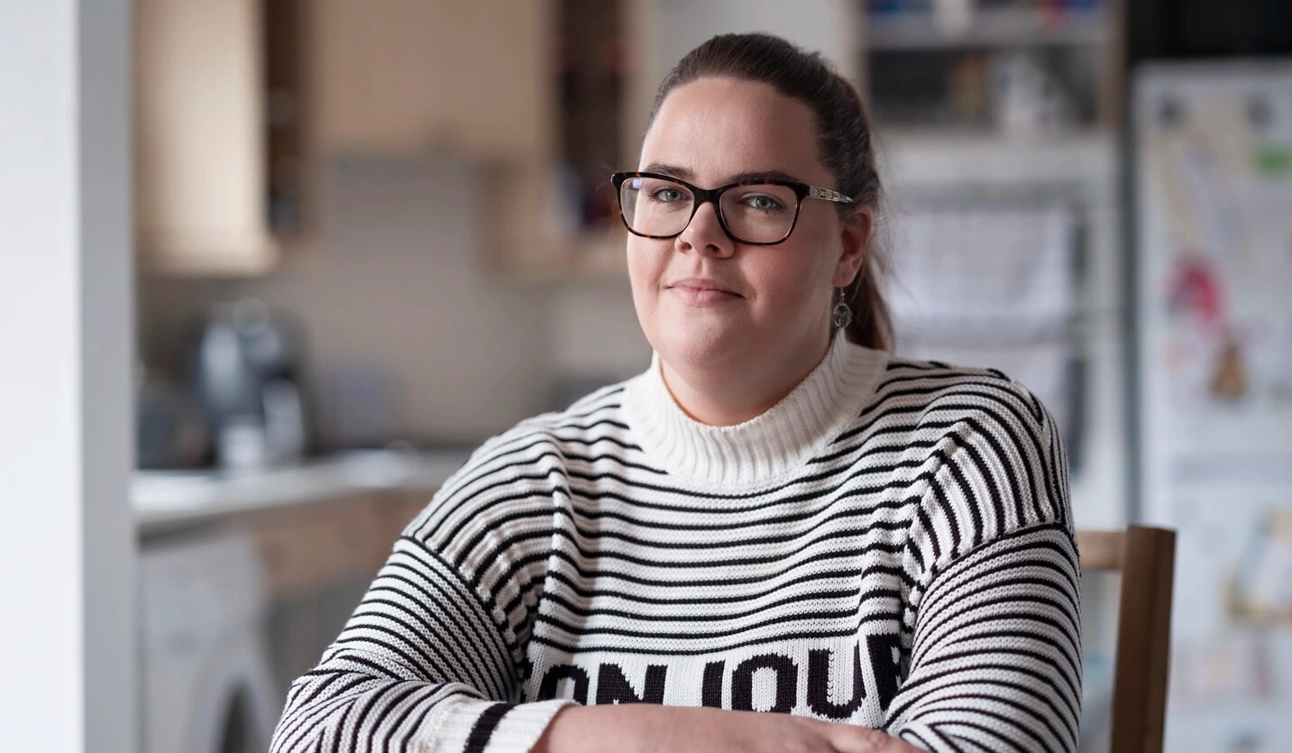 Sarah, een gebruiker van intermitterende katheters die leeft met MS, zit aan een tafel. 